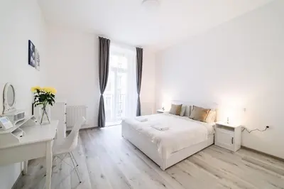 a white bedroom with a white bed and a desk at New apartments near Dancing house in Prague