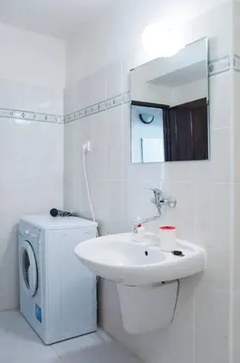 a white bathroom with a sink and a washing machine at Dlouha Apartment 2BD in Prague