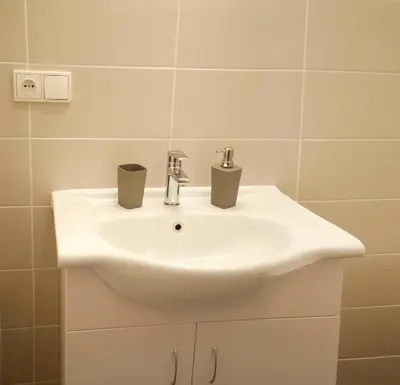a white bathroom sink with two cups on it at Residence Krakovska 5 in Prague