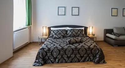 a bedroom with a bed with a comforter and a couch at Residence Krakovska 5 in Prague