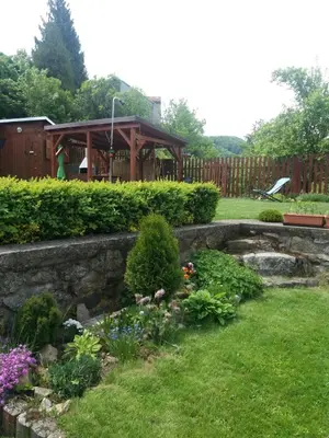 a garden with a stone retaining wall and a gazebo at Stará Sázava in Sázava