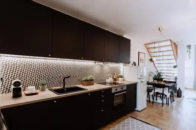 a kitchen with black cabinets and a white refrigerator at Loft apartment with balcony in centre in Prague