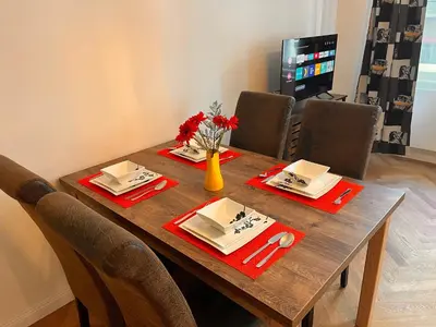 a wooden table with red napkins and a vase of flowers on it at Riverbridge Apartments Prague in Prague