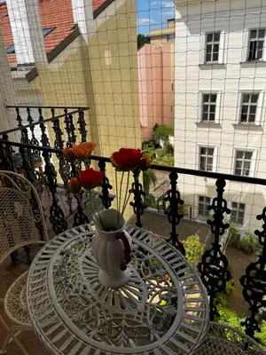 a glass table with a vase of flowers on a balcony at Le Papillon de Bohème in Prague
