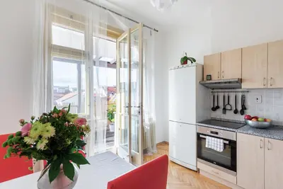 a kitchen with a white refrigerator and a table with a vase of flowers at Castle View Apartment Prague in Prague