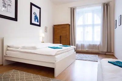 a white bedroom with two beds and a window at Large 3 BDR APT in the heart of Prague in Prague