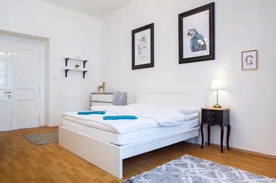 a white bedroom with a bed and a table with a lamp at Large 3 BDR APT in the heart of Prague in Prague