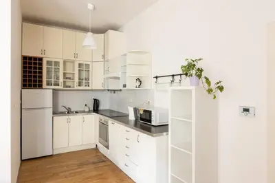 a white kitchen with white cabinets and a microwave at City Centre Garden Apartment with parking in Prague