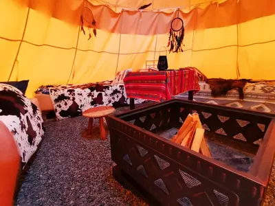 a room with a tent with a couch and a table at Teepee Camp Lounky in Chodouny
