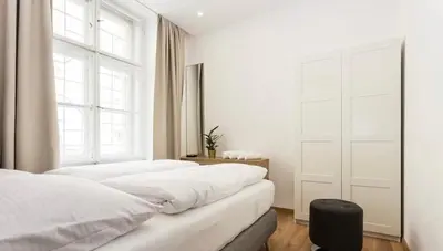 a white bedroom with two beds and a window at Luxury Apartment on Wenceslas Square in Prague