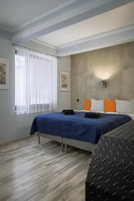a bedroom with a bed with blue sheets and orange pillows at Residence Řipská 26 in Prague