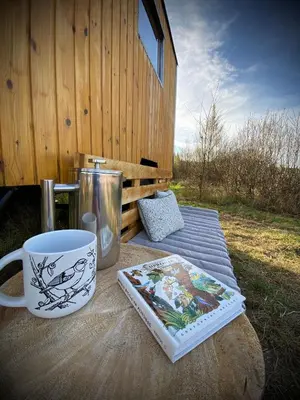 a table with a coffee mug and a book on it at Maringotka Za Trnkou in Točník