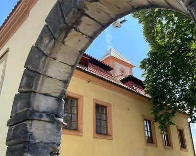 an archway in front of a yellow building with a tower at Královské apartmá kolonáda in Poděbrady