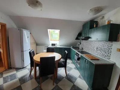 a kitchen with green cabinets and a table and chairs at Apartmán v blízkosti města Štětí in Štětí