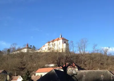 a large white building on top of a hill at Kamenný dům s výhledem na zámek 20km od Prahy in Nižbor