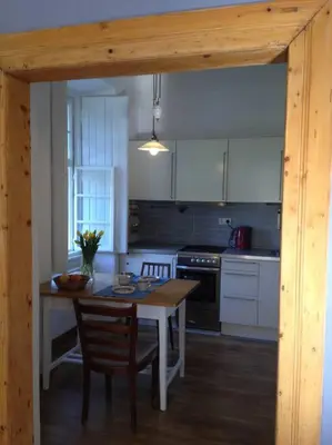 a kitchen with a table and chairs and a kitchen with white cabinets at Kamenný dům s výhledem na zámek 20km od Prahy in Nižbor