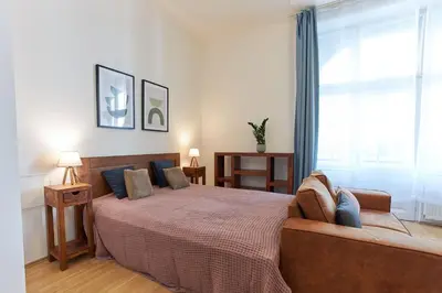 a bedroom with a bed with a couch and a window at Narodni - Old Town Residence in Prague