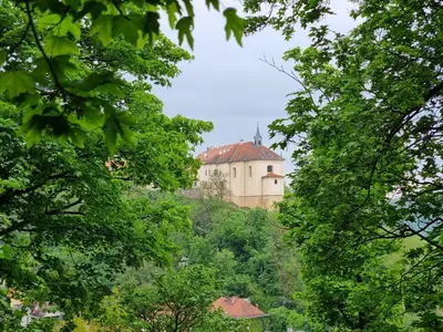 a building on top of a hill with trees at Nižbor samostatný domek v zahradě in Nižbor