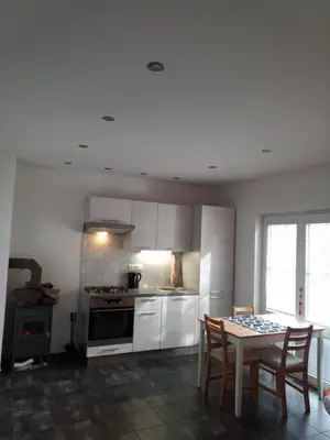 a kitchen with white cabinets and a table and chairs at Nižbor samostatný domek v zahradě in Nižbor