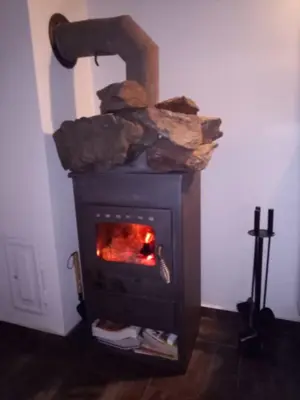 a wood stove with a fire in a room at Nižbor samostatný domek v zahradě in Nižbor