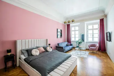 a bedroom with a bed and a pink wall at LuxePair Suites Near Prague Castle in Prague
