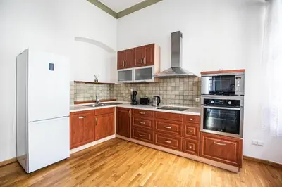 a kitchen with wooden cabinets and a white refrigerator at LuxePair Suites Near Prague Castle in Prague