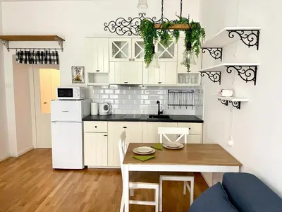 a small kitchen with white cabinets and a wooden table at Centrum Bohemia Apartment in Prague