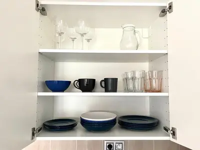 a pantry with plates and wine glasses on shelves at Centrum Park Studio in Prague