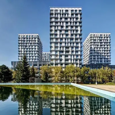 two tall buildings in a city with a reflection in the water at Centrum Park Studio in Prague