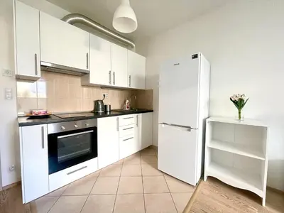 a kitchen with white cabinets and a refrigerator at Centrum Park Studio in Prague