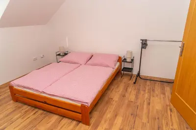 a bedroom with a bed with pink sheets and wooden floors at Apartmán Tereza in Poděbrady