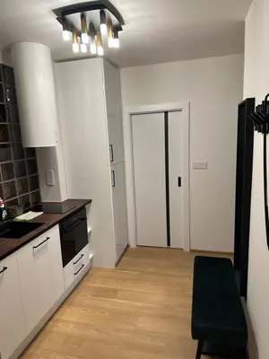 a kitchen with white cabinets and a wooden floor at Apartmán Panenská in Prague