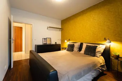 a bedroom with a large bed with a yellow wall at AuriApartments Karlín 2KK s terasou a parkováním in Prague