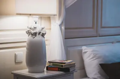 a white vase sitting on a table next to a bed at Extraordinary Prague Apartment in Prague