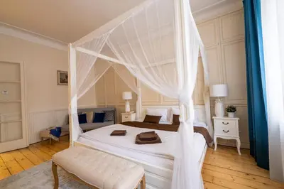 a bedroom with a white canopy bed with a bench at Extraordinary Prague Apartment in Prague