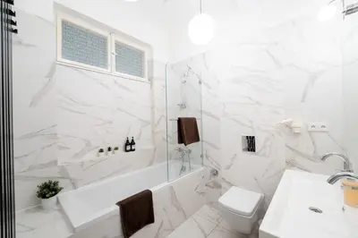 a white bathroom with a tub and a toilet and a sink at Extraordinary Prague Apartment in Prague